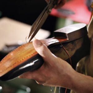 Schoenmaker knipt draad bij de afwerking van een Goodyear welt