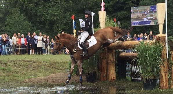 Ruiter en paard tijdens een afsprong het water in.